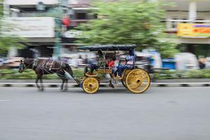 yogyakarta, indonesia - mayo de 2022 retrato de movimiento borroso del paseo turístico a delman en jalan malioboro. delman es un vehículo tradicional de java, indonesia. foto