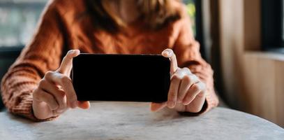 trabajador masculino manos sosteniendo el teléfono inteligente en la oficina moderna oscura foto