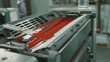 Worker at Polygraphy printing industry use Red paint on ink roller video