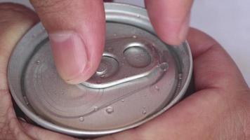 Closeup hands are opening aluminum can of coffee with a gas inside, with a sensitive focus. Water drop droplets on wet aluminum can. video