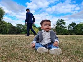 lindo bebé pequeño está posando en un parque público local de la ciudad de luton de inglaterra reino unido foto