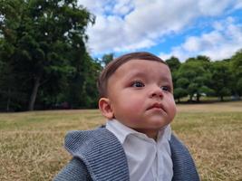 lindo bebé pequeño está posando en un parque público local de la ciudad de luton de inglaterra reino unido foto