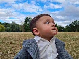 lindo bebé pequeño está posando en un parque público local de la ciudad de luton de inglaterra reino unido foto