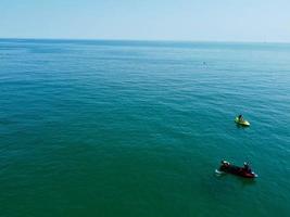 High Angle Footage and Aerial view of Ocean with High Speed Boats, People are having fun and enjoying hottest weather at Bournemouth Beach Sea Front of England UK. photo