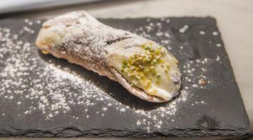 Cannoli is a dessert from Sicily, Italy consisting of ricotta cheese, powdered sugar and pistacchio photo