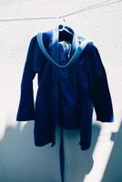 Close up on brazilian jiu jitsu or judo blue kimono uniform hanging next to a wall photo