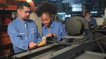 Asian male and female African American engineers in safety uniform work by inspecting machines' voltage current, checking, and maintaining at manufacture factory, electric system service occupations. video
