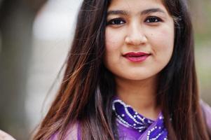 Close up portrait of indian hindu girl at traditional violet saree posed at street. photo