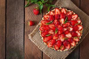 Tart with strawberries and whipped cream decorated with mint leaves photo