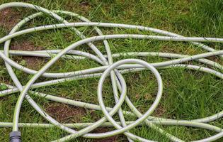 Top view of hosepipe on grass and cobblestone surfaces. Minimalistic conception photo