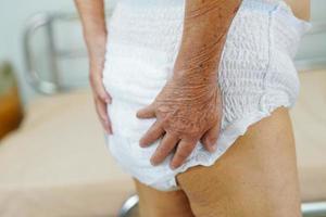 Asian elder senior woman patient wearing adult incontinence diaper pad in hospital. photo