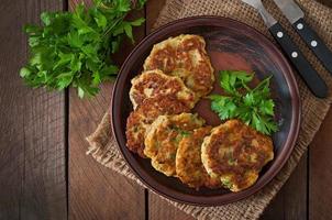 Zucchini pancakes with parsley on a wooden table photo