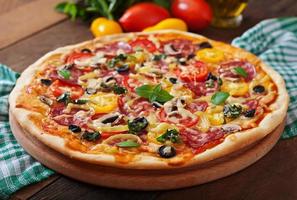 Pizza with salami, tomato, cheese and olives photo