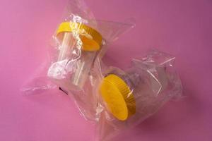 Two sterile medical containers for urine testing, wrapped in foil photo