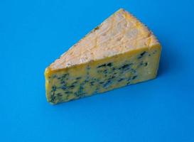 Closeup on a piece of moldy cheese on a blue background photo