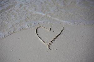 corazones dibujados en la arena de una playa foto