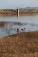 silhouette of fisherman on wood boat at lake. photo