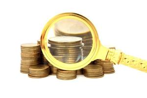 Magnifier and gold coins. On a white background. photo