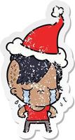 distressed sticker cartoon of a crying girl wearing santa hat vector