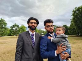 2 Young Asian Males are Walking with an Infant Baby Boy at Local Public Park of Luton England UK photo