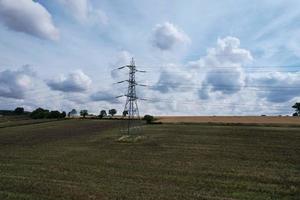 High Voltage Power Supply Poles with Cables Running Through British Farmlands and Countryside, Aerial high angle view by drone's camera. photo