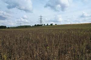 High Voltage Power Supply Poles with Cables Running Through British Farmlands and Countryside, Aerial high angle view by drone's camera. photo
