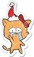 distressed sticker cartoon of a cat wearing santa hat vector