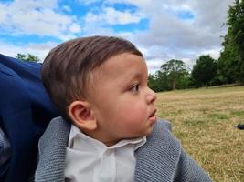 lindo bebé pequeño está posando en un parque público local de la ciudad de luton de inglaterra reino unido foto