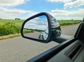 View into the side mirror of a black sports car while driving. photo