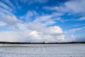 Beautiful clouds in the sky looking over a snow covered agricultural field. photo