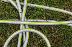 Top view of hosepipe on grass and cobblestone surfaces. Minimalistic conception photo