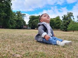 lindo bebé pequeño está posando en un parque público local de la ciudad de luton de inglaterra reino unido foto