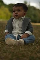 lindo bebé pequeño está posando en un parque público local de la ciudad de luton de inglaterra reino unido foto