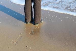 Human feet in black shoes at a baltic sea beach in northern Germany. photo