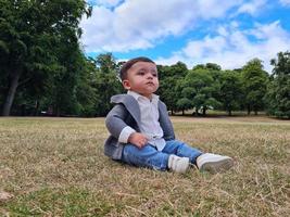 lindo bebé pequeño está posando en un parque público local de la ciudad de luton de inglaterra reino unido foto