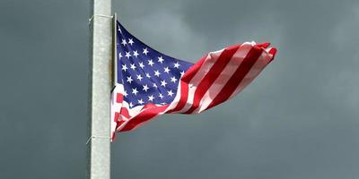 USA flag at a flagpole moving slowly in the wind against the sky photo