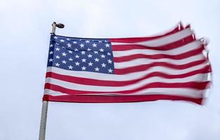 USA flag at a flagpole moving slowly in the wind against the sky photo