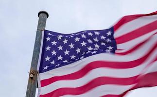 USA flag at a flagpole moving slowly in the wind against the sky photo