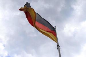 Germany flag at a flagpole moving slowly in the wind against the sky photo