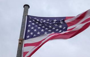 USA flag at a flagpole moving slowly in the wind against the sky photo