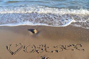 la palabra alemana ostsee mar báltico y un corazón escrito en la arena de la playa. foto