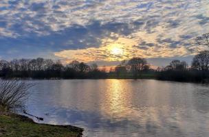 bella y romántica puesta de sol en un lago de colores amarillo y naranja foto