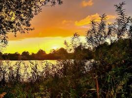 Beautiful and romantic sunset at a lake in yellow and orange colors photo