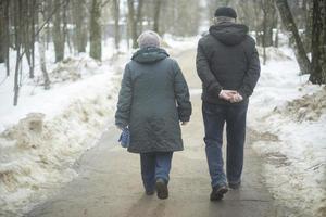 Man and woman walk through park in winter. People on street. Walk around city. photo