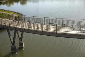 Pedestrian bridge on water. Bridge with railings. Details of park in city. photo