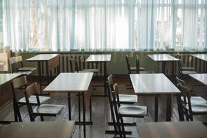 Desks for students at school. Classroom is empty. Chairs and tables are in row. photo