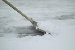 Shovel snow removal. Tool for cleaning snowdrift. Janitor cleans road from precipitation. photo