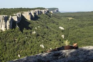 A man walks through a cave city in the summer. Tourists watch the rocks. Rest on top. Tourist route in the Crimea. Crimean mountains in the travel season. photo