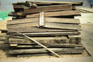 Old boards stand in heap. Broken planks lie on beach. photo