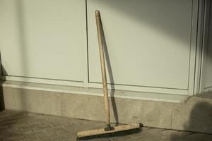 Mop for cleaning is against wall. Broom for cleaning room. Object near wall. photo